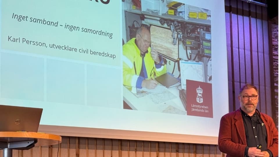 En man som står framför en stor projektorduk och föreläser